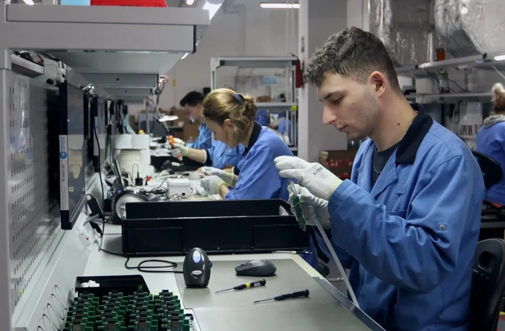 TECHTO technician inspecting an assembled circuit board at a test station